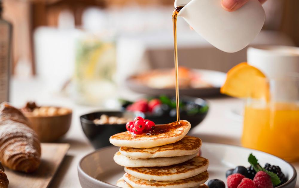 Pancakes with maple syrup, berries, and orange juice for breakfast.