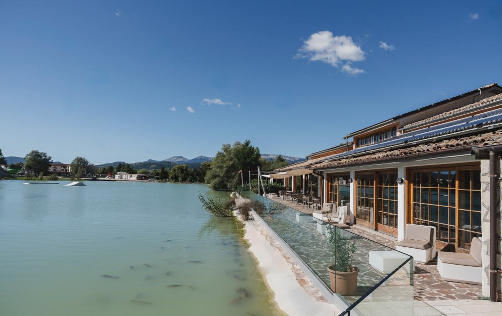 Peaceful lake with panoramic restaurant, surrounded by mountains and nature.