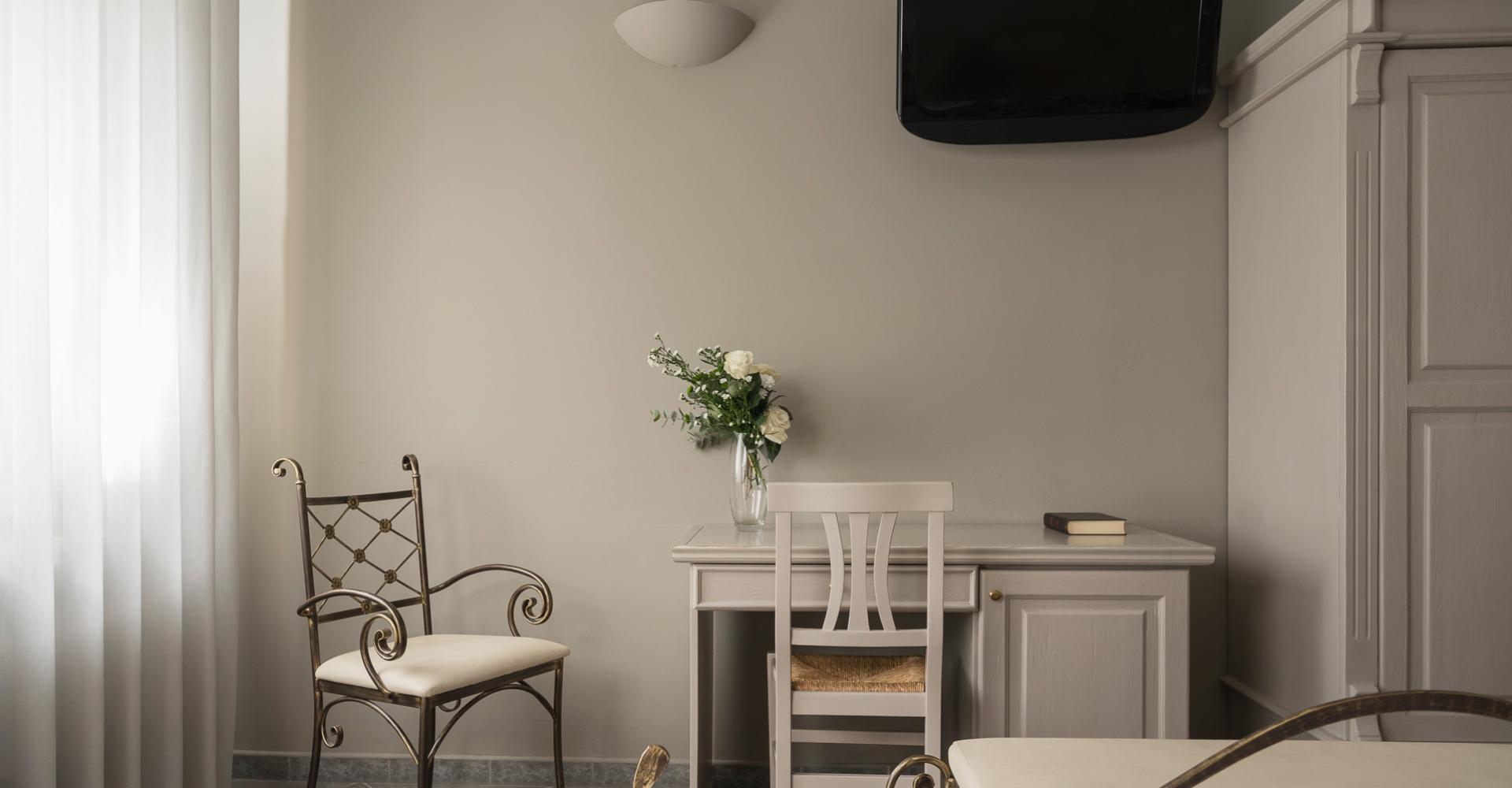 Elegant room with light furniture, fresh flowers, and a wall-mounted TV.